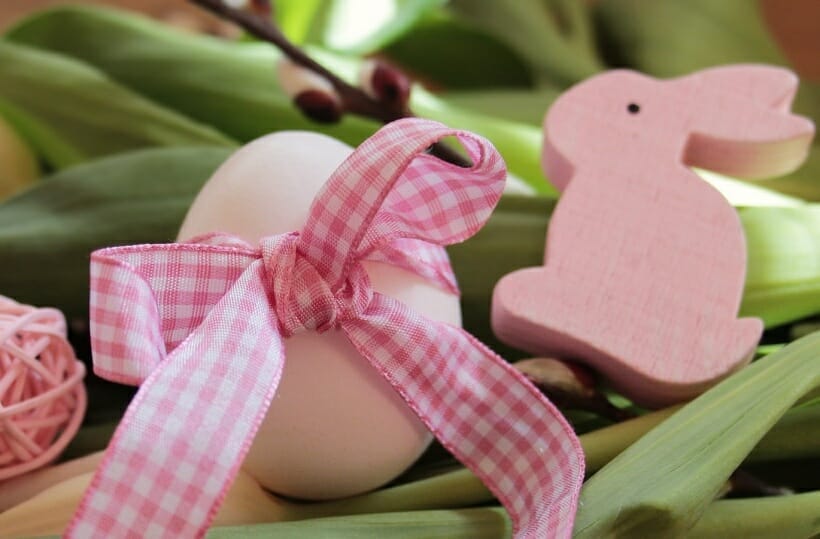 A naturally dyed pink easter egg with a pink gingham bow and a pink bunny peep.
