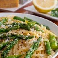 Closeup view of lemon pasta dish with asparagus and shredded parmesan cheese on top.