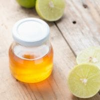 Homemade honey cough syrup with halved limes around it.