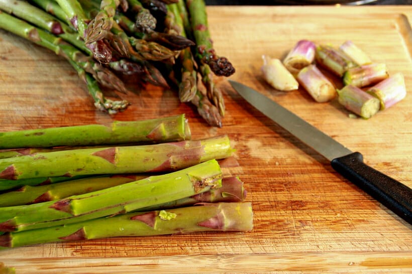Asparagus on a cutting board with the woody ends cut off.