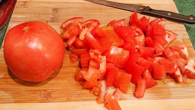 Chopping up a tomato on a bamboo cutting board.