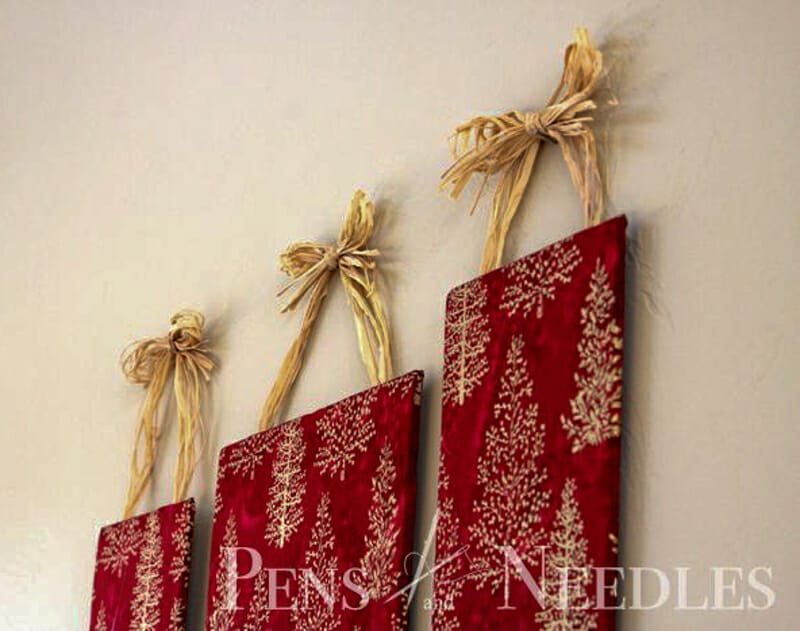 Red fabric with gold trees and snowflakes mounted on boards as wall decor.