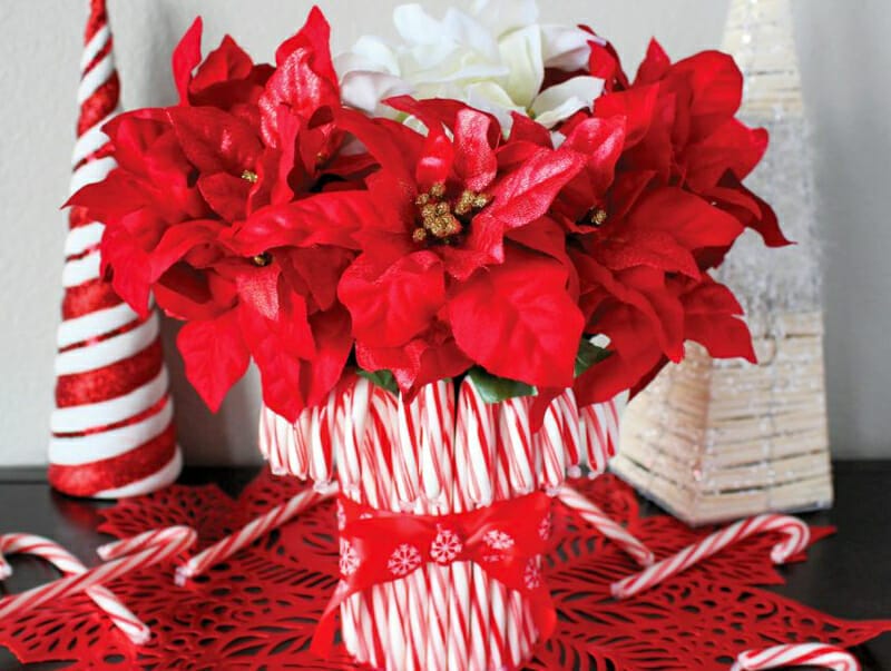 A candy cane vase filled with poinsettias. 