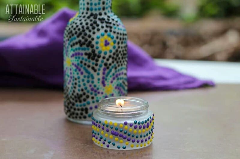 A glass bottle and a small mason jar candle decorated with 3-D paint dots.