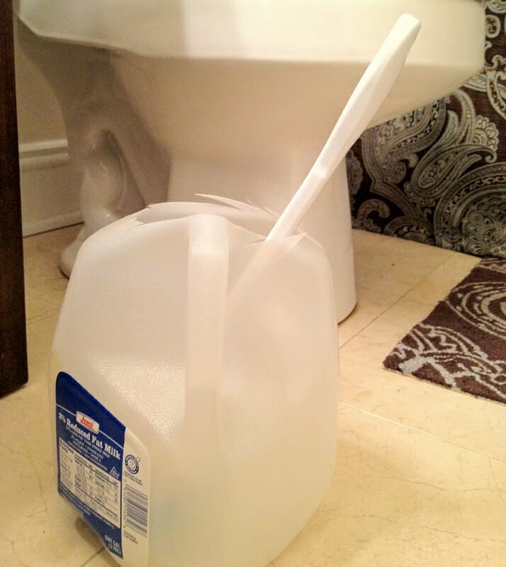 A toilet brush holder made from a milk jug.