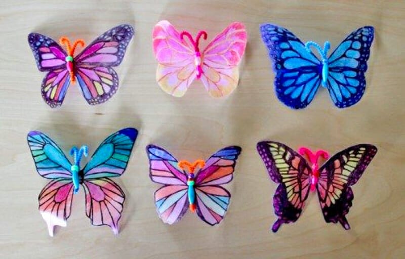 Six multicolored butterflies made out of milk jugs.