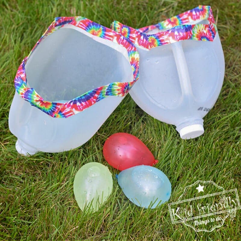 Two cut up milk jugs with tie dye duct tape around the cut edges and a stack of water balloons.