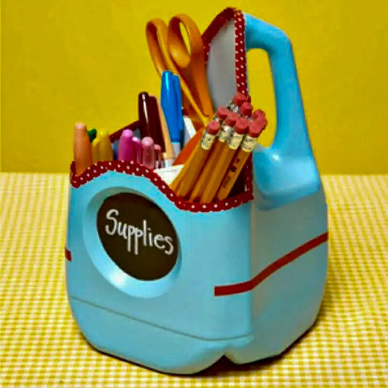 A blue painted milk jug organizing school supplies.