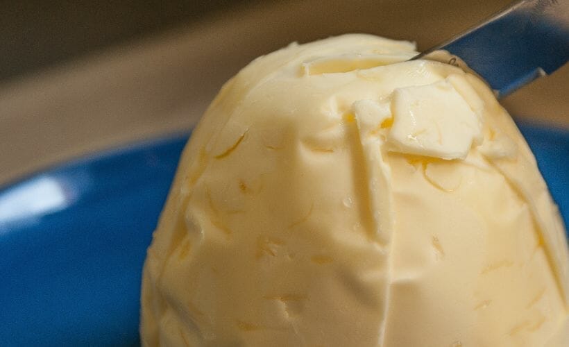 A knife in homemade butter on a blue plate.