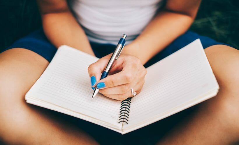 Sitting in the garden with a notebook and pen to set homestead goals.