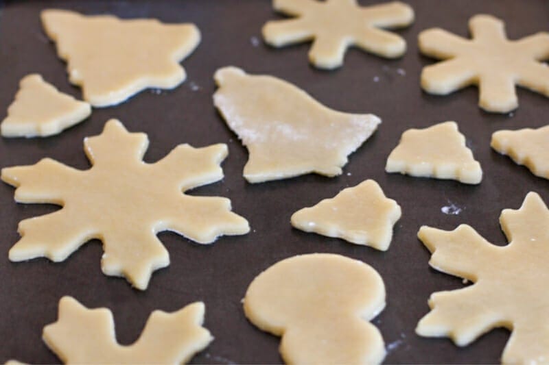 Sugar cookies freshly cut in holiday shapes and ready for baking.