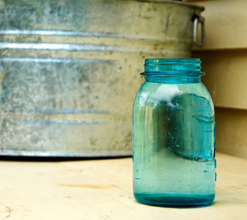 A blue mason jar next to a metal wash bin.
