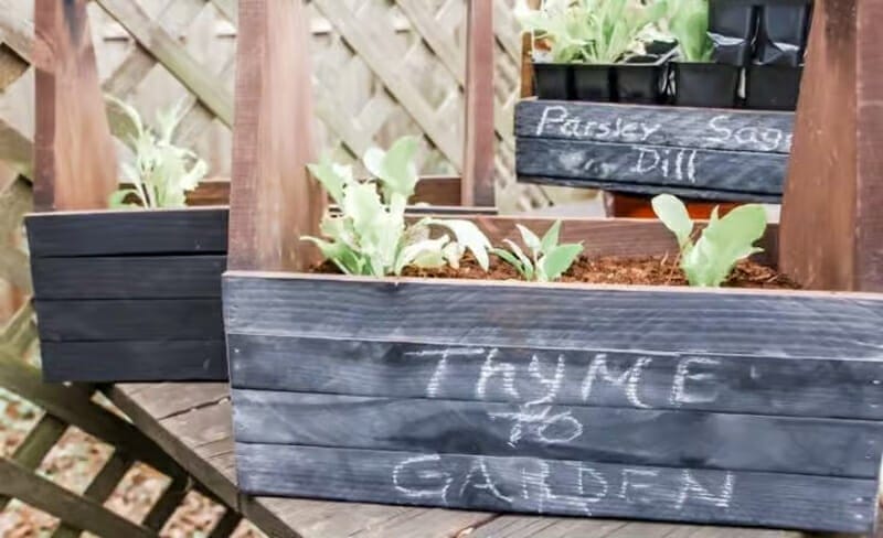 Outdoor herb planter painted with chalkboard paint and "thyme to garden" written on it with chalk.