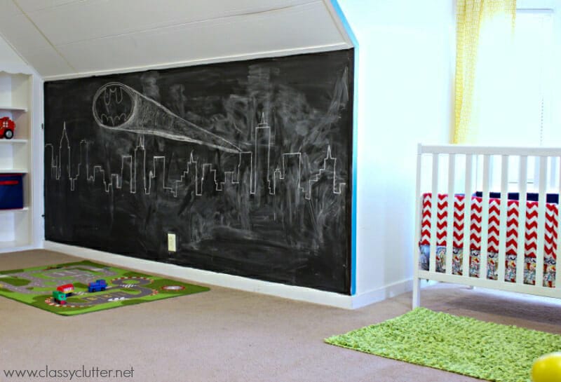 A wall painted in chalkboard with Gotham City and the Batman logo drawn on it with chalk.