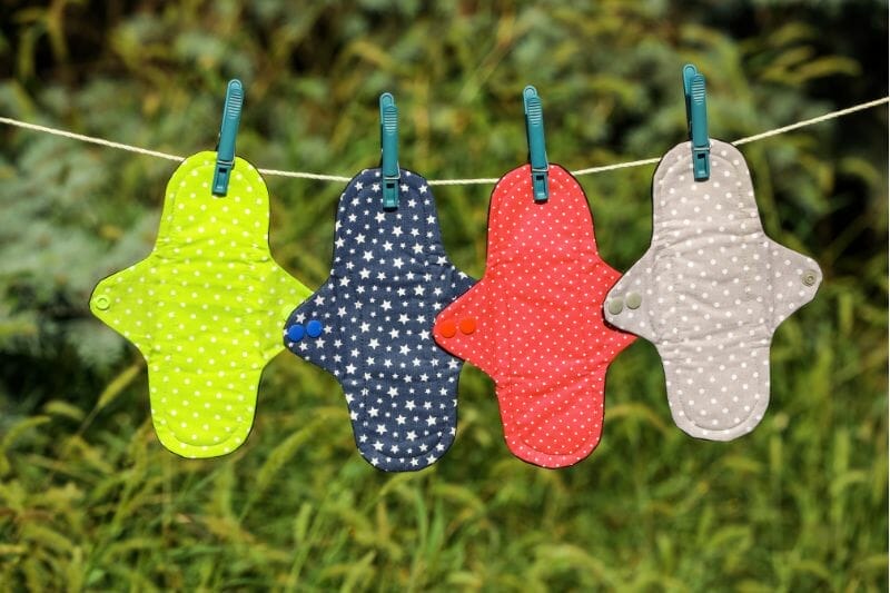 Brightly colored reusable period pads hung up on a clothesline outdoors.